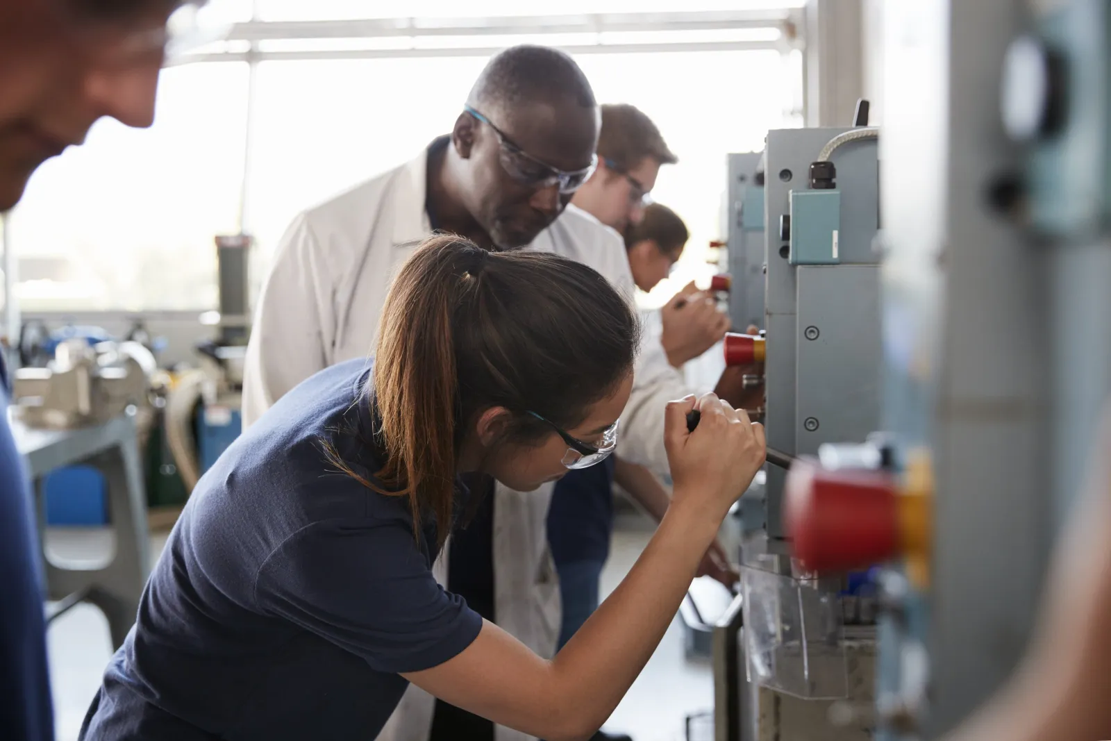 Engineer training an apprentice at a workshop machine