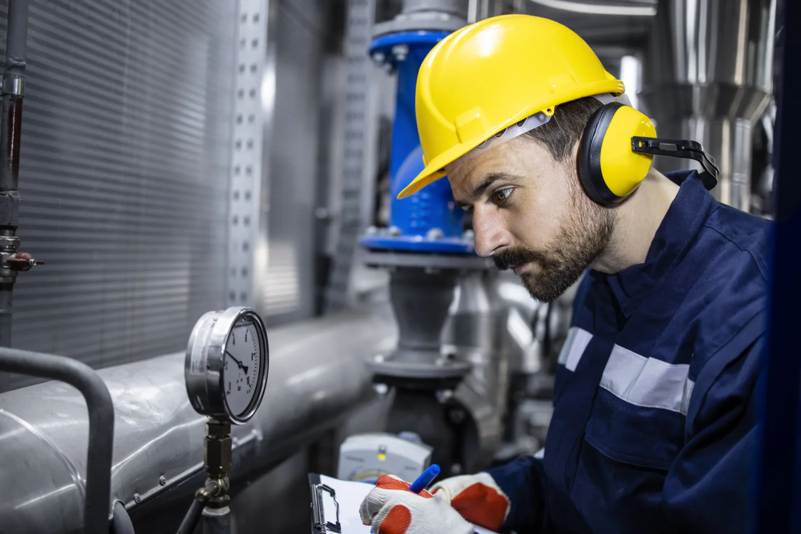 Technician checking pressure gauges on plant pipework