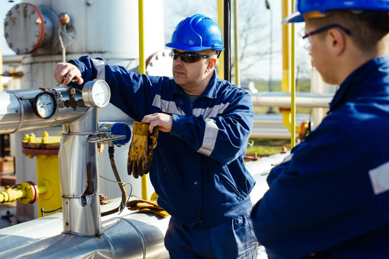 Field technicians checking a gauge on oil and gas pipework