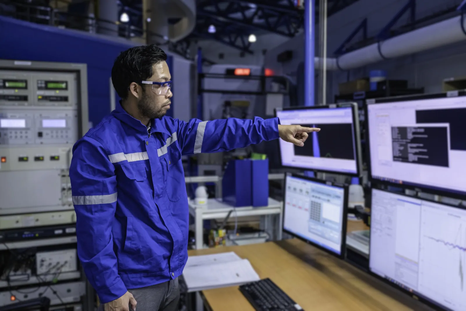 Engineer pointing at process control screens in a factory control room